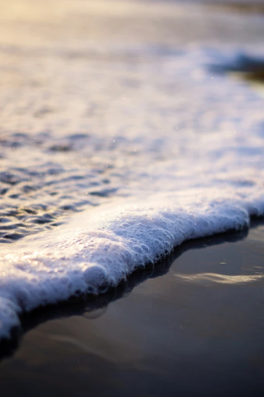 a small wave rolls towards the shore on an ocean beach