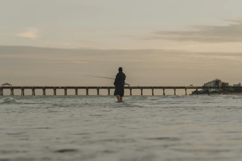 a person stands in the water while holding a fish rod