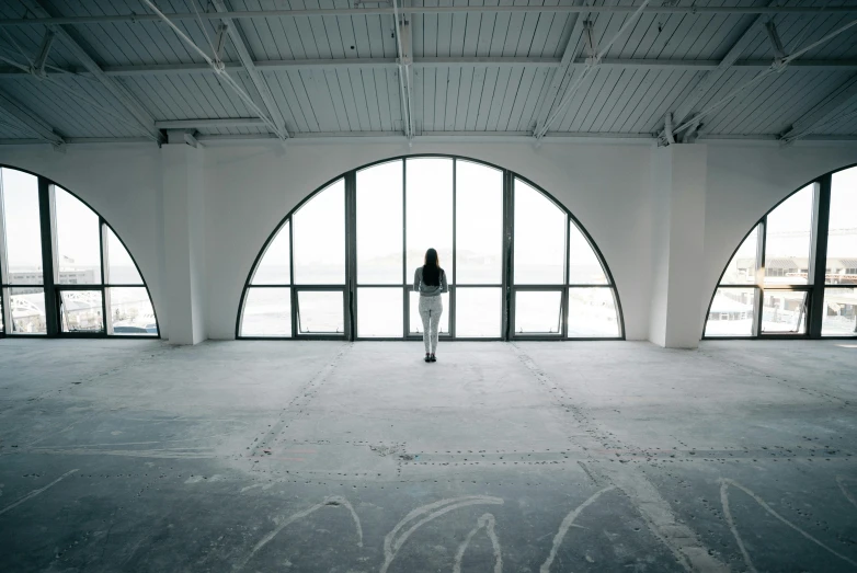 a person standing near a giant window in an empty room