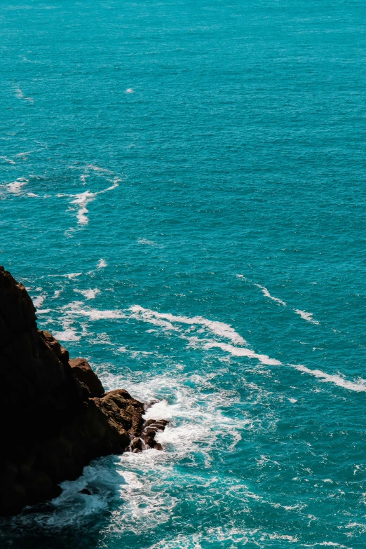 a person on a boat sailing in the water near a cliff