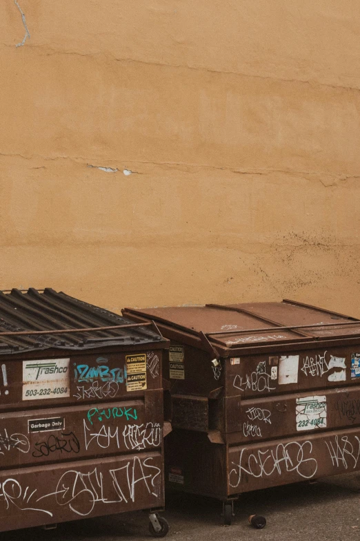 two suitcases with stickers are sitting in front of a brown wall