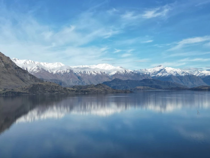 the mountains and water in the foreground are reflected in the still water