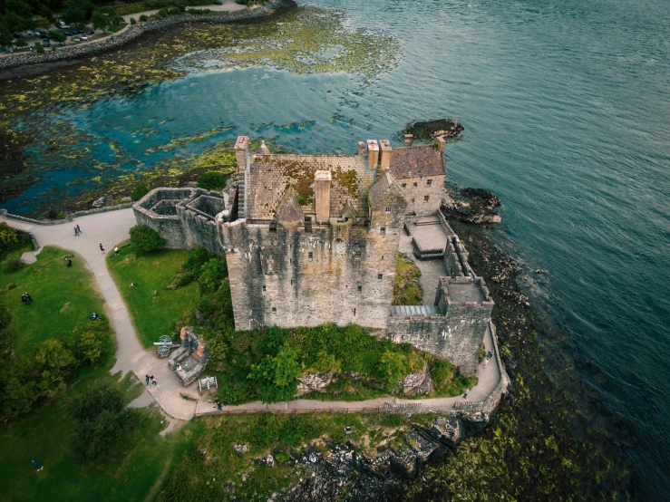 an old castle on the coast with a green park area next to it