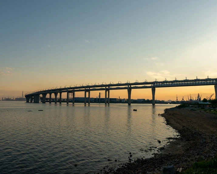 a bridge is over looking the water at sunset