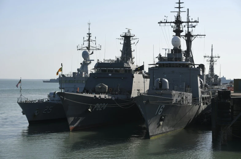 two navy ships are in the water beside each other