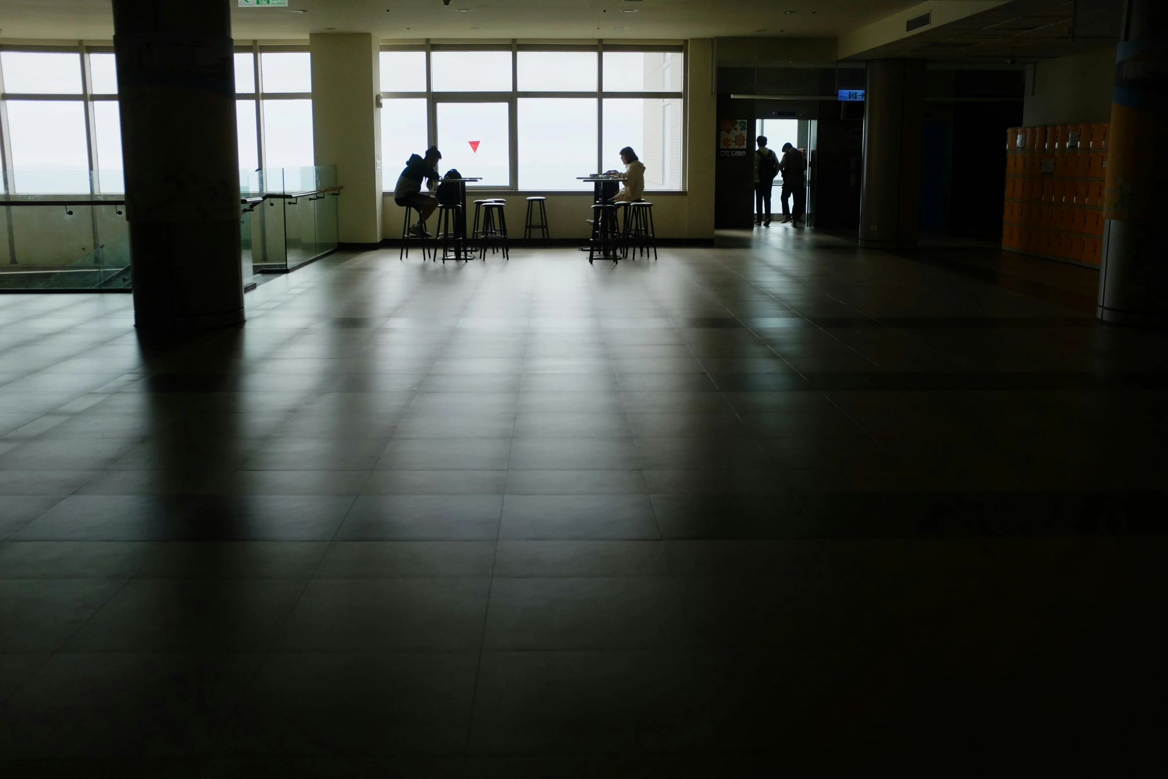 people standing in front of large windows, waiting for their turn