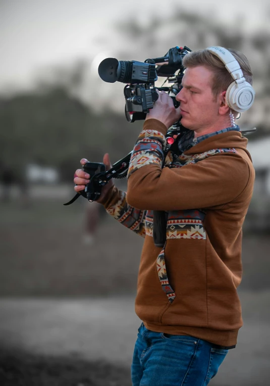 a guy standing with a camera, looking in the distance