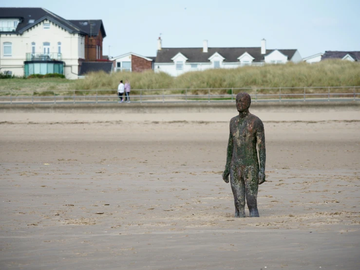 a person with a hat and bodysuit standing on the sand