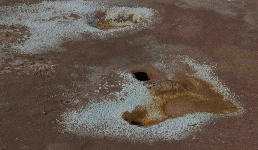 a dirt surface with white powder and a hole in the middle