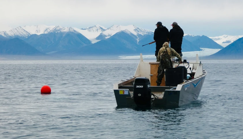 two men in a small fishing boat fishing and watching another man