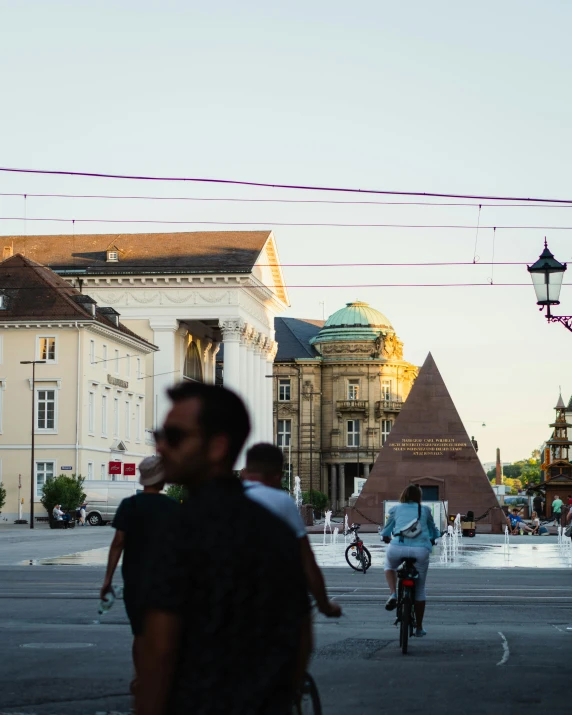 people riding bicycles near some buildings and a building