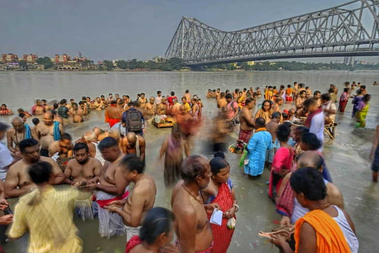 many people bathe in the waters near an indian bridge