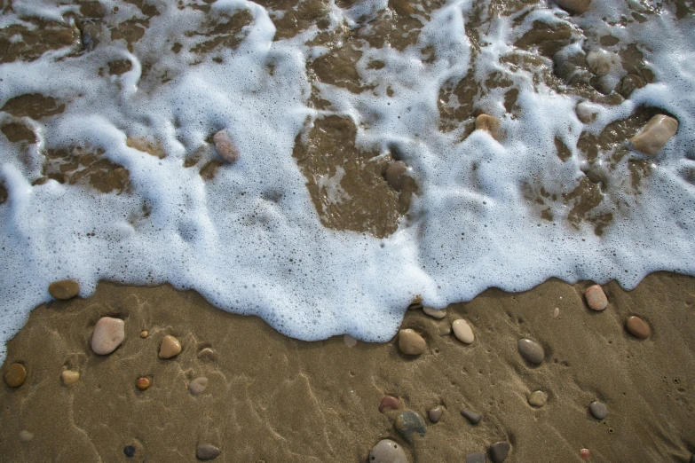 foamy water in the ocean with small rocks near by