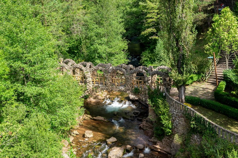 an aerial view of a bridge that crosses the middle of a stream