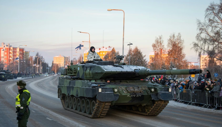 the tank with people riding it driving through the streets