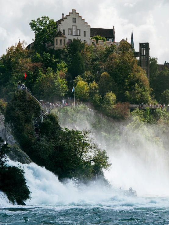 water gushing down a cliff into a river, with a castle on the hill in the distance