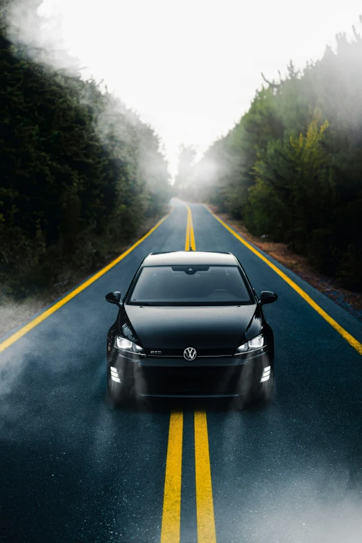 a car traveling down a country road with fog in the air