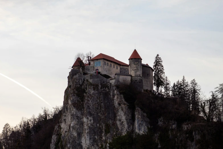 there is a building on a rocky cliff above the trees