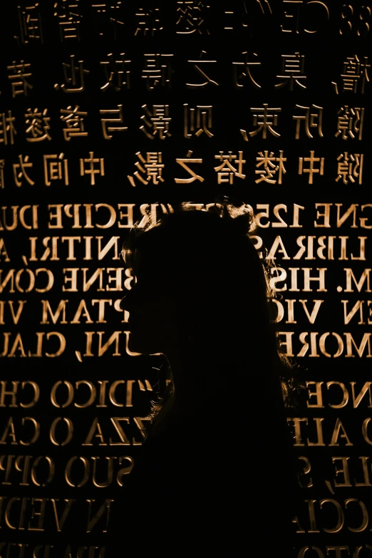 a silhouette of a person sitting in the darkness with the name written behind them