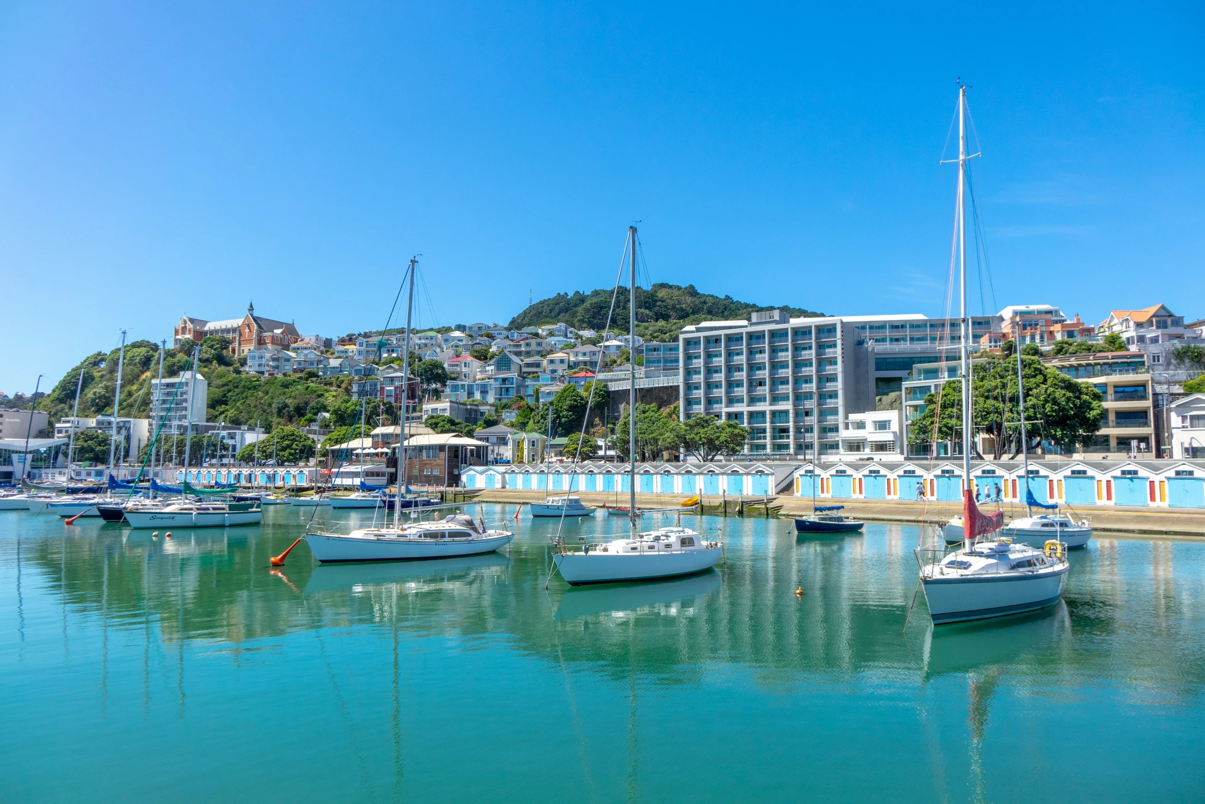 several boats floating in the clear water near buildings