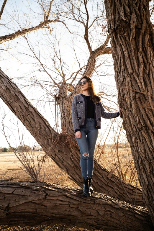 a woman posing on top of a log in a forest