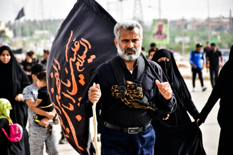 people dressed in black carrying flags and banners