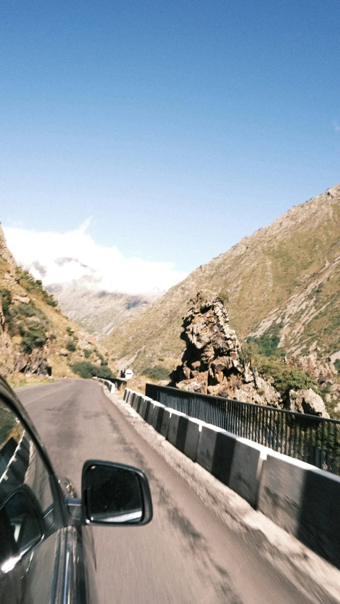 a long car drives down a road with mountains