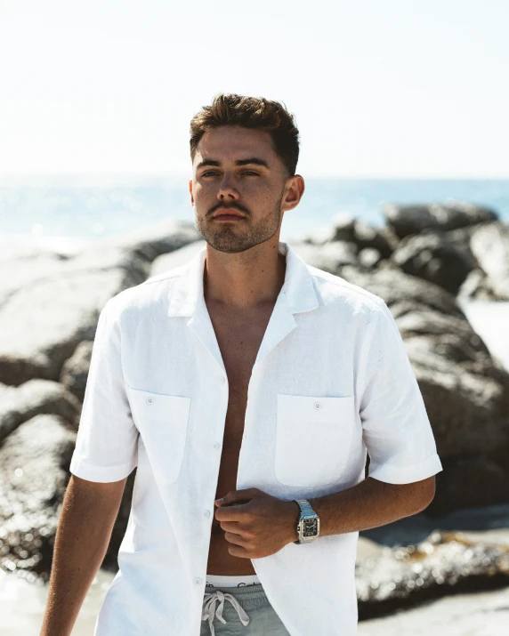 a man standing on the beach near rocks and ocean