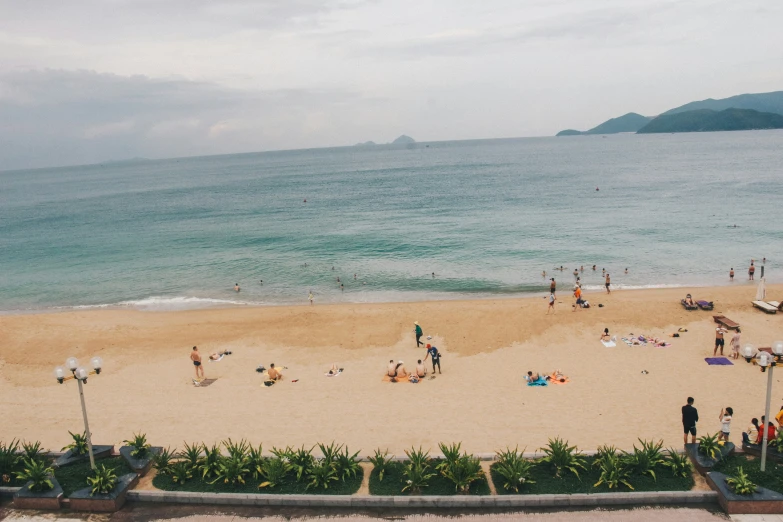 many people at a beach, some with sun umbrellas