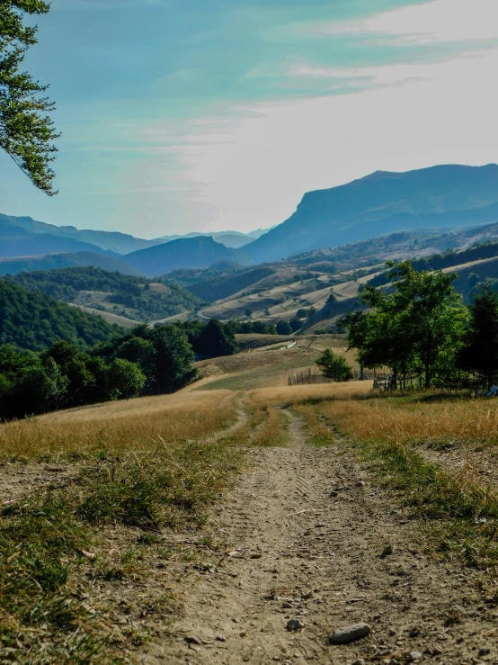 a dirt path surrounded by mountains in the distance