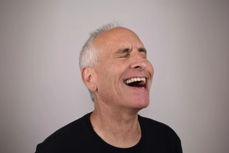 an older man wearing a black t - shirt smiles