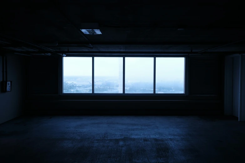 a dimly lit empty room with open windows