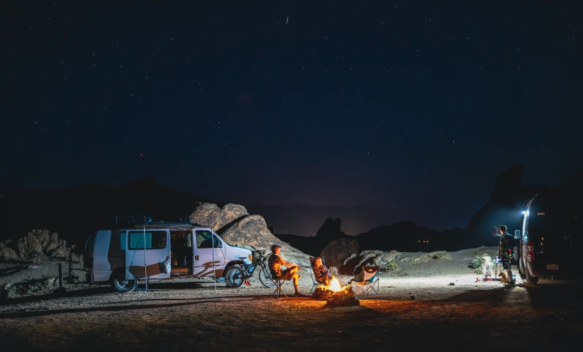 a camping site with campers and fire during night