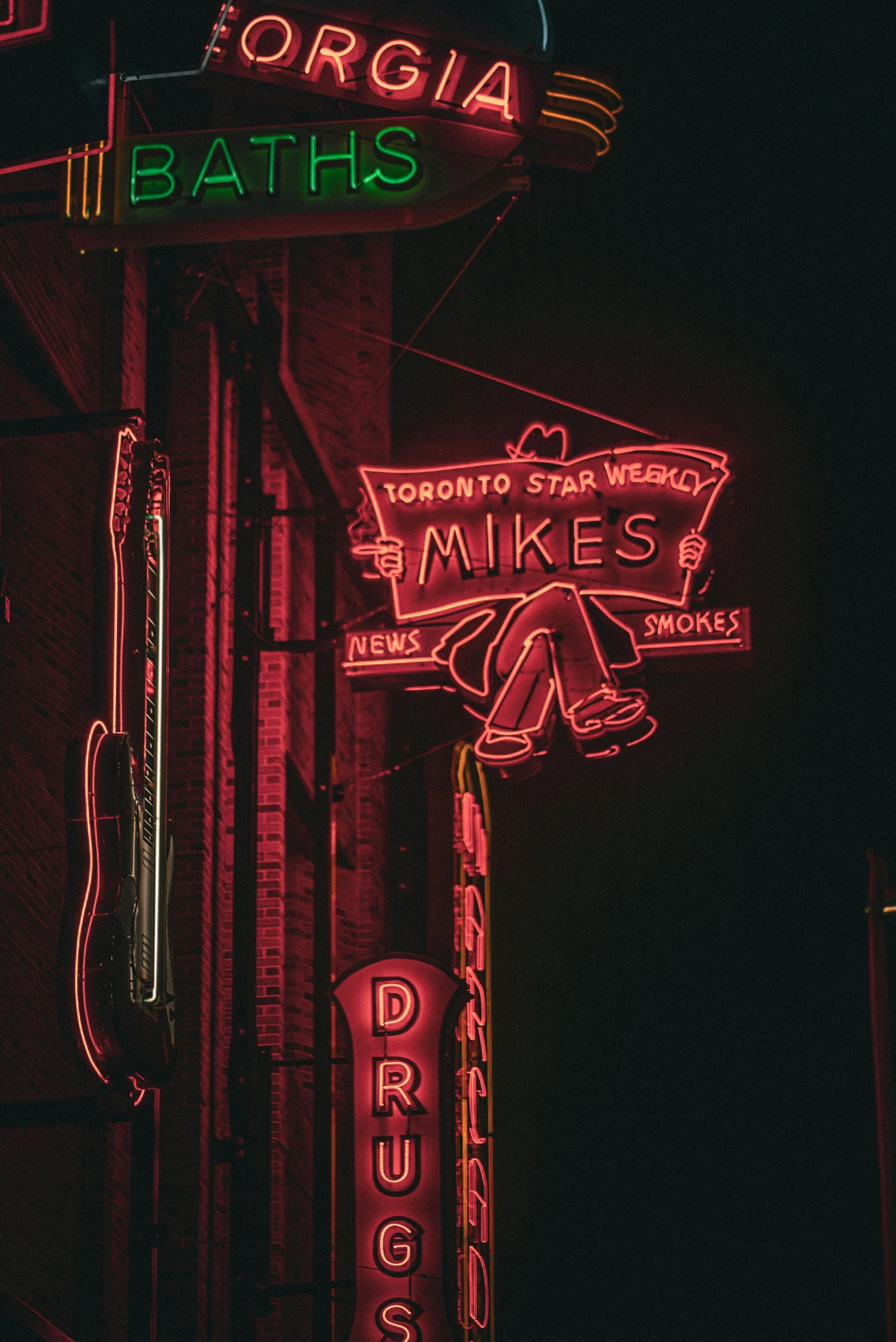 neon signs hang from the side of a building