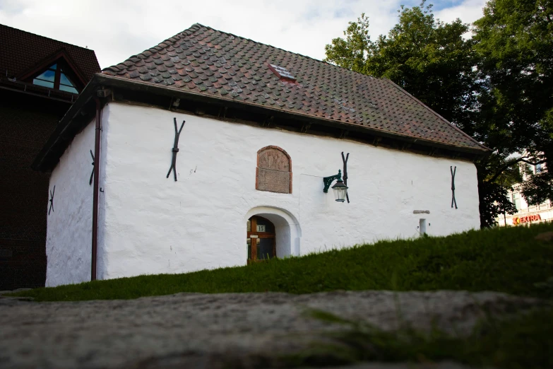 a very small white building with three windows and a green lawn