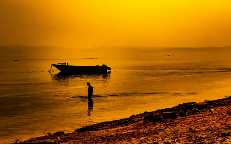 an orange and yellow po of a man standing in a boat