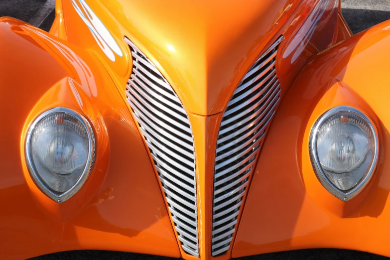 close up of an orange classic car front grille and headlights