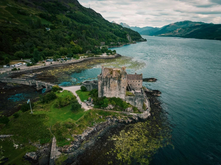 the large castle is near a river and mountains