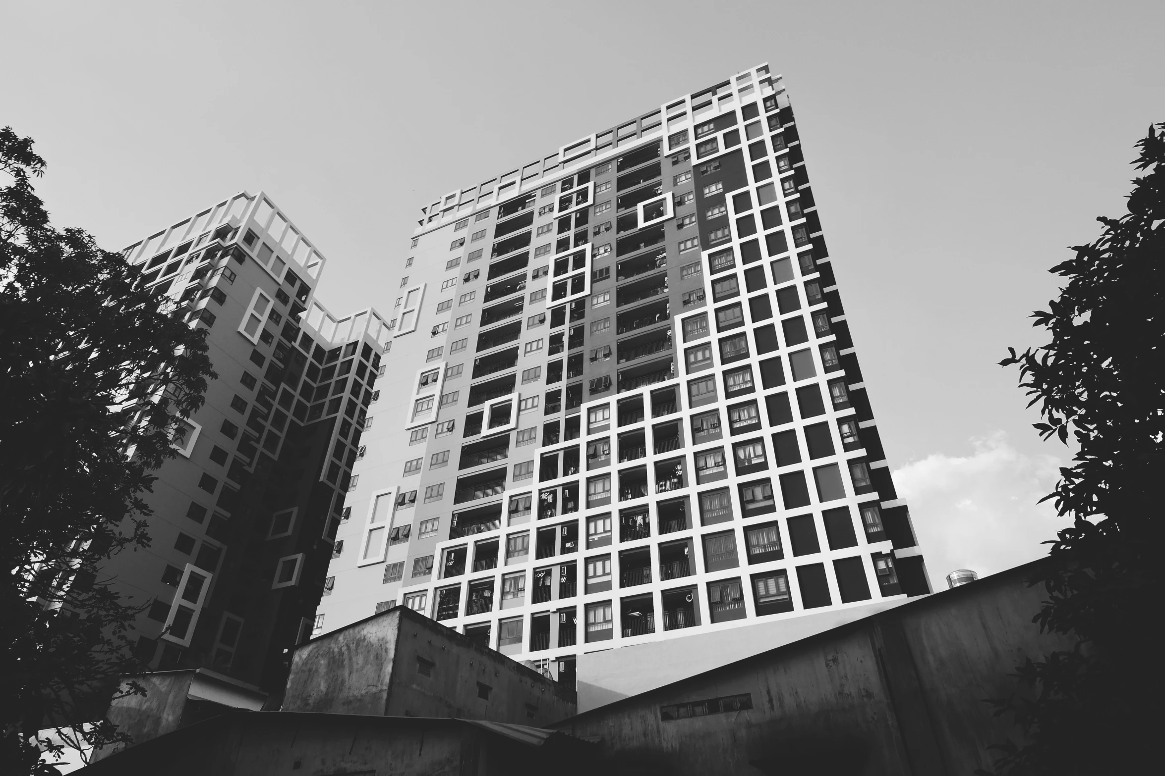 two tall buildings with glass windows and a sky background