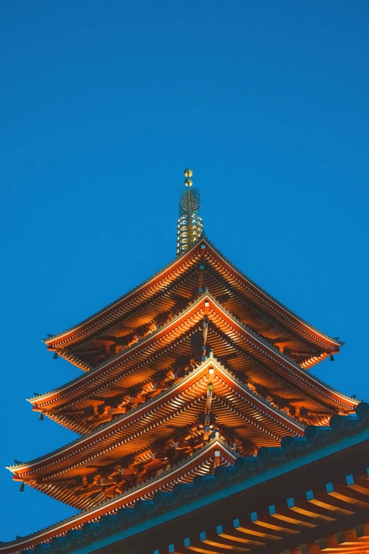 the roof of an asian building illuminated up in the evening sky