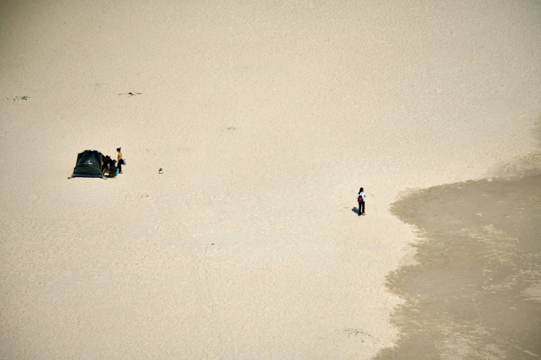 two people are standing in the sand at the beach