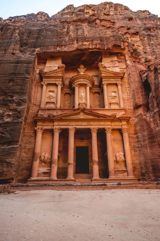 large building with several carved faces in side of cliff