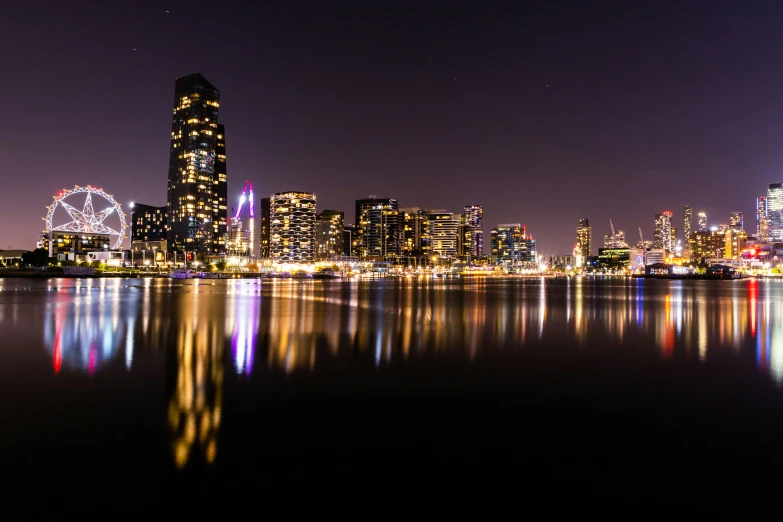 an illuminated city skyline at night next to water