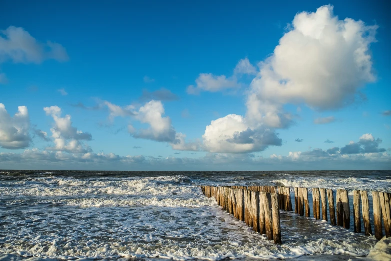 clouds over water near a beach pier in the ocean