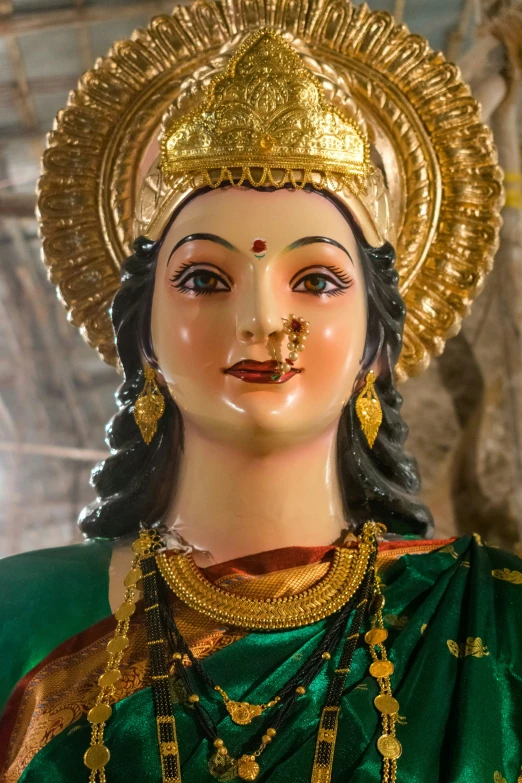 an idol statue with golden accents wearing a green sari