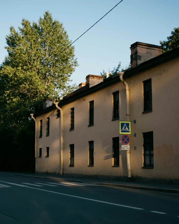 a large beige building sits beside the tree