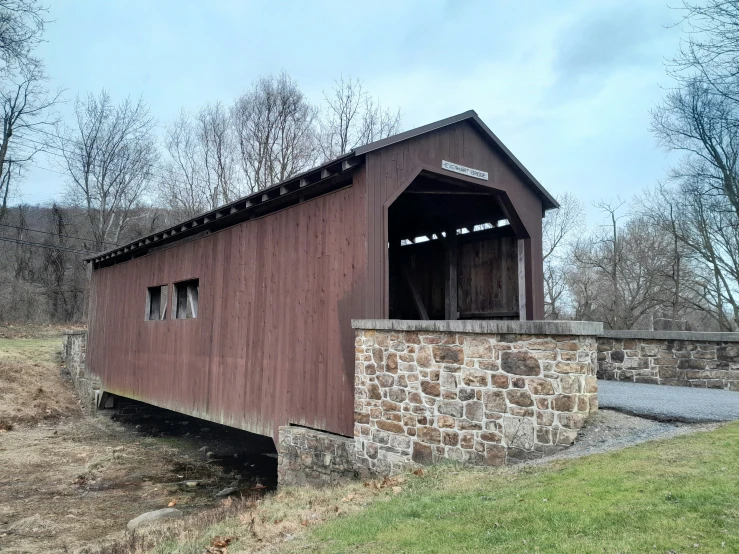 a wooden covered bridge that has a gravel ramp leading to it