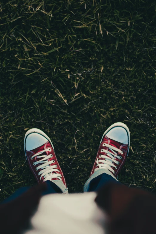 a person wearing white and red shoes with grass