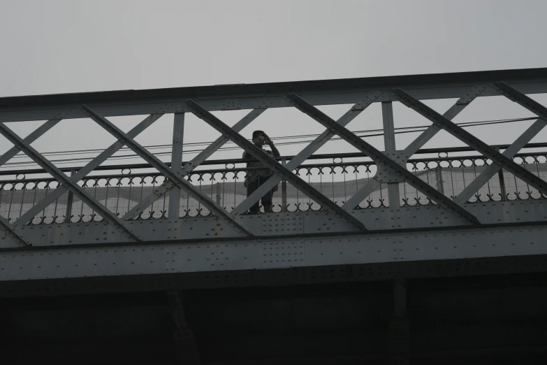 a man walking across a bridge on top of a metal platform