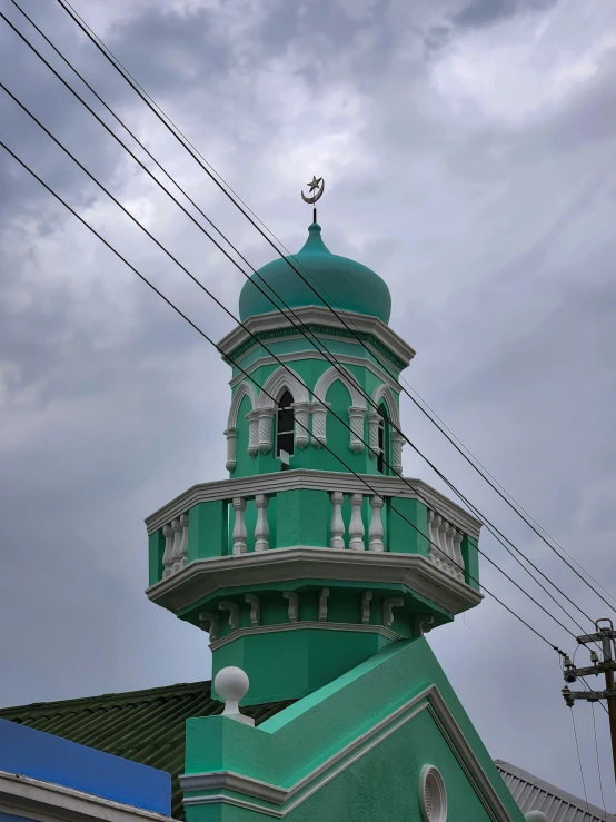 an architectural building with a circular green steeple and green trim on a cloudy day